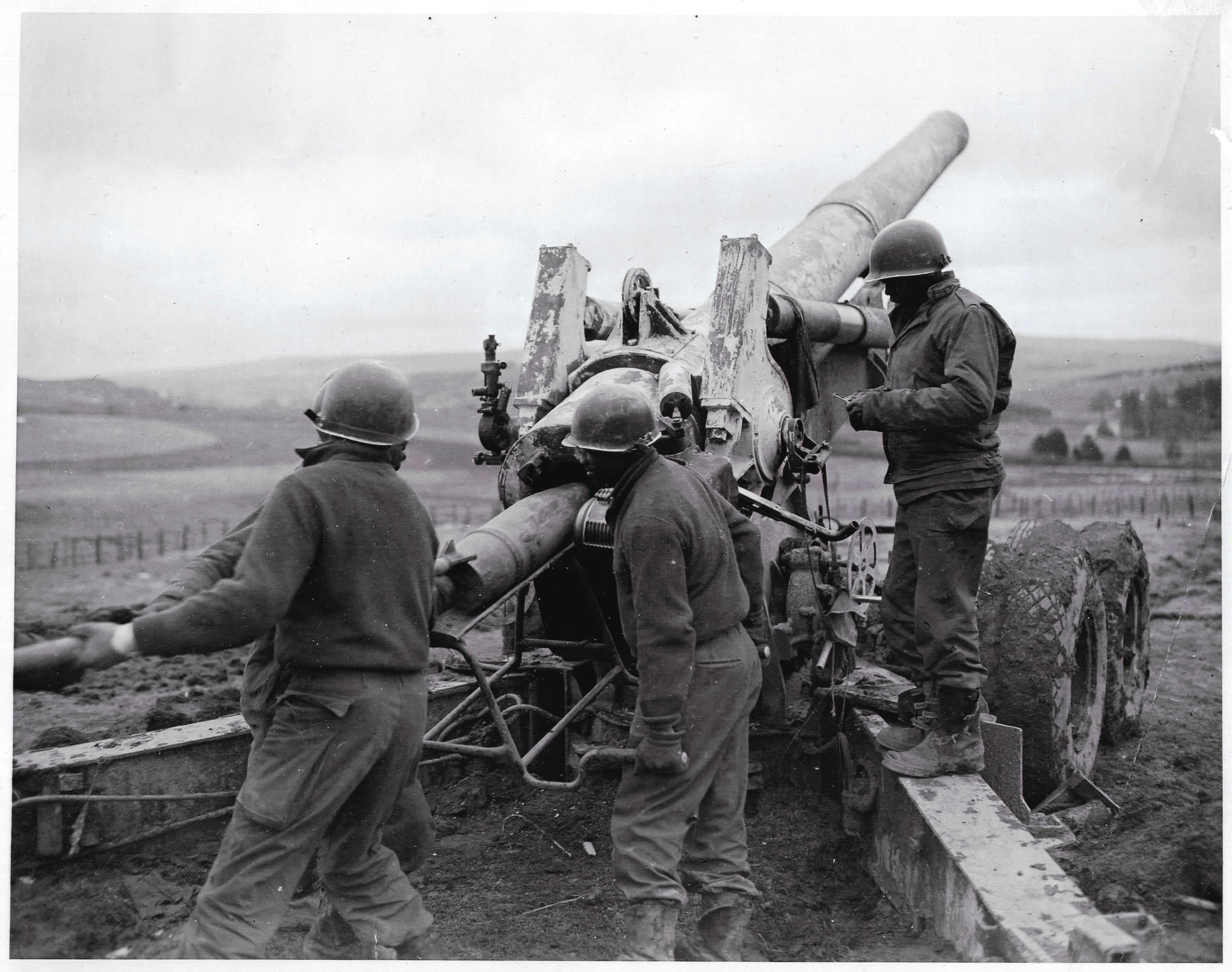 An 8-inch howitzer of the 578th Field Artillery Battalion. The gun is in the middle of the photograph, while standing around it are Black American soldiers.