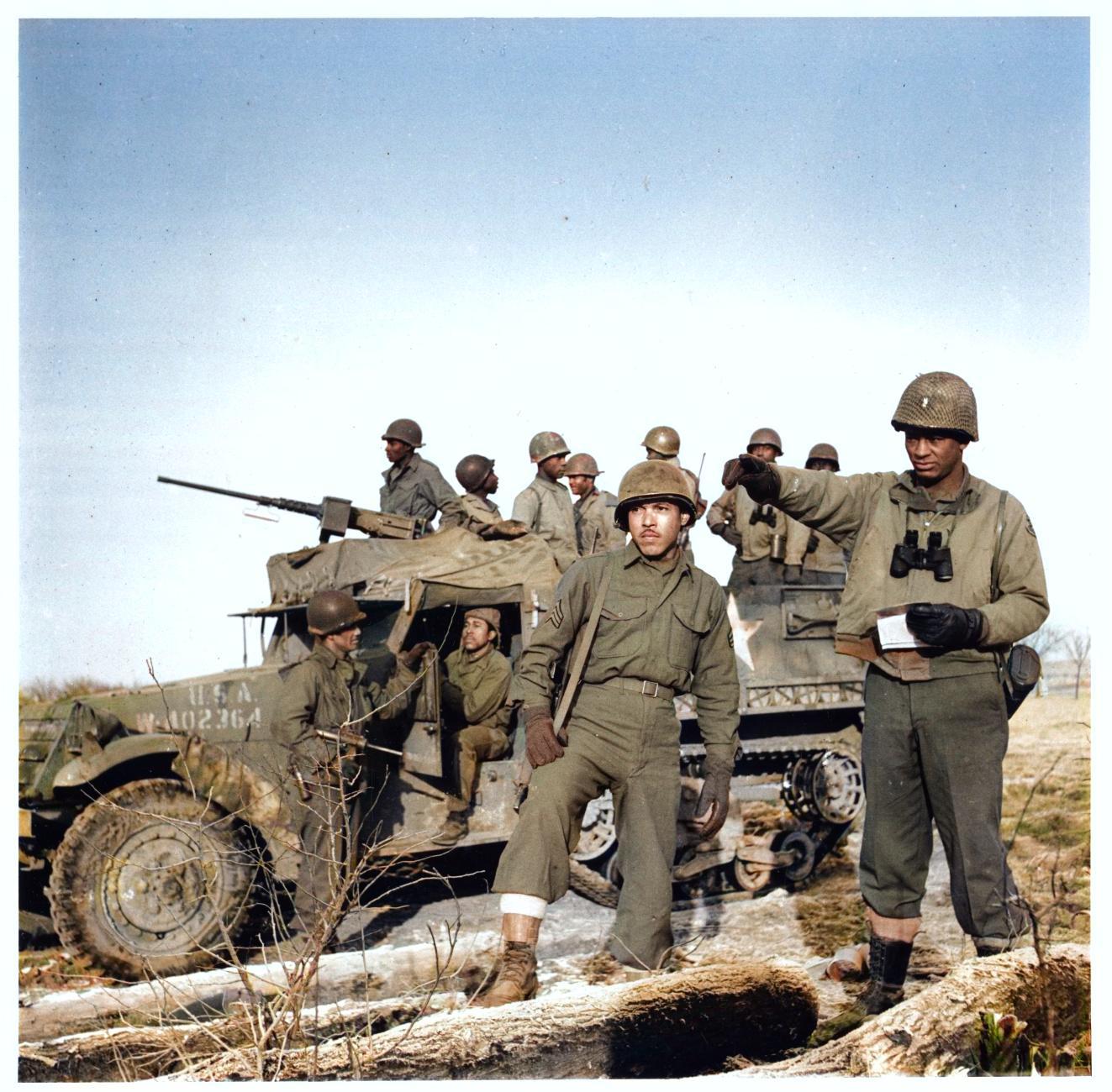 An image of a half-track of the 614th Tank Destroyer Battalion. In front of the half-track are two soldiers of the 614th TD Bn.