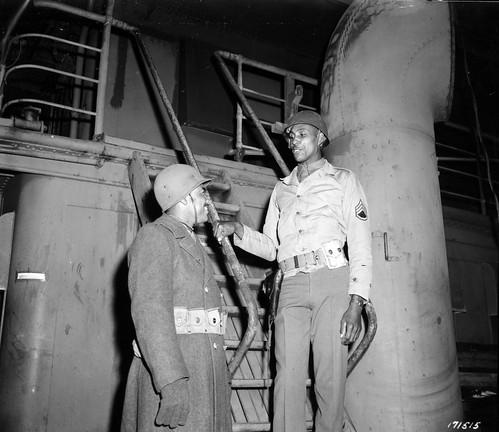 Historical image showing Private Isaac Bartell, left, is instructed by S/Sgt. Thomas Blackstone. of Black American soldiers during WWII