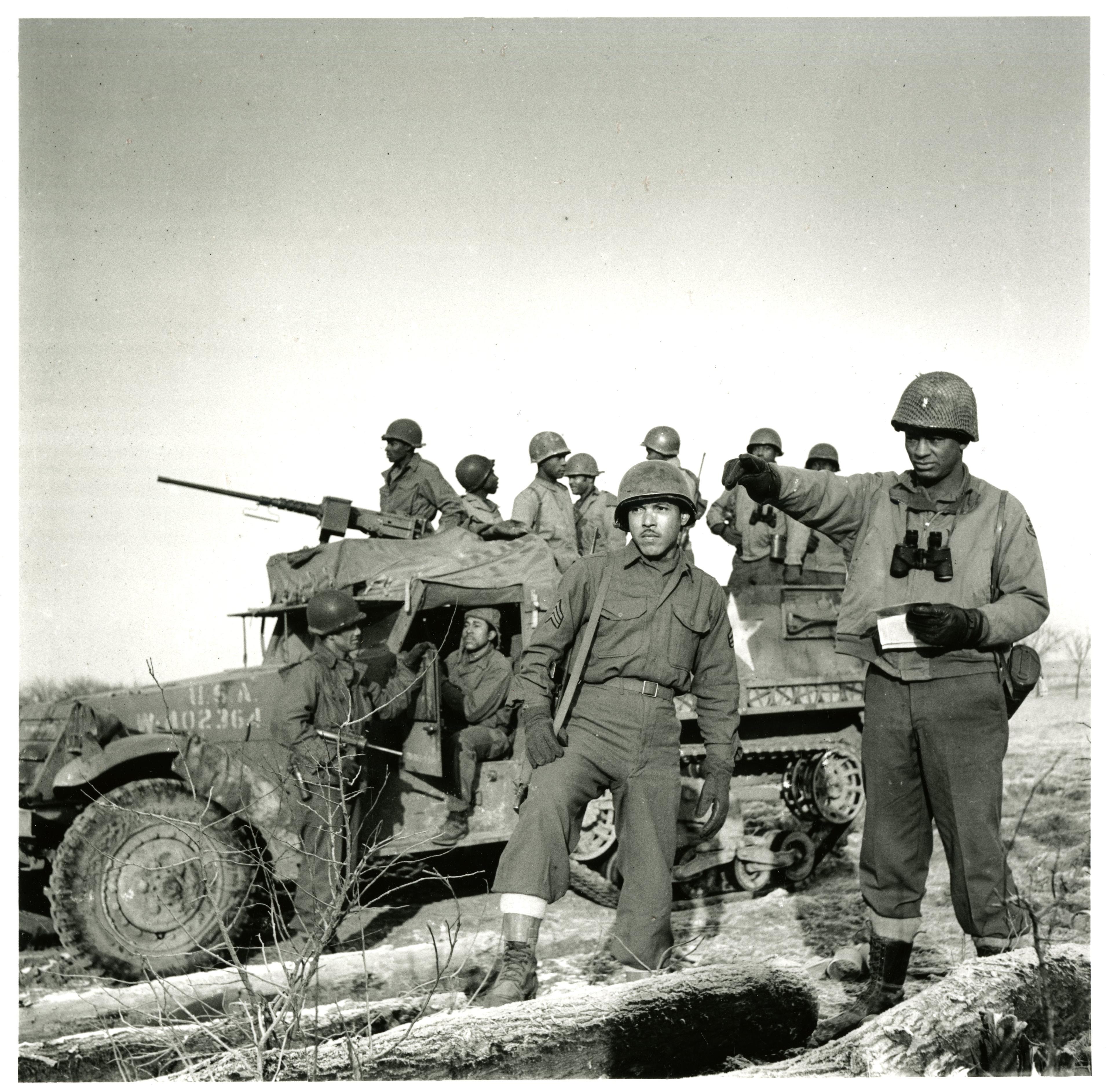 Historical image showing An officer and an enlisted man in front of a halftrack of Black American soldiers during WWII