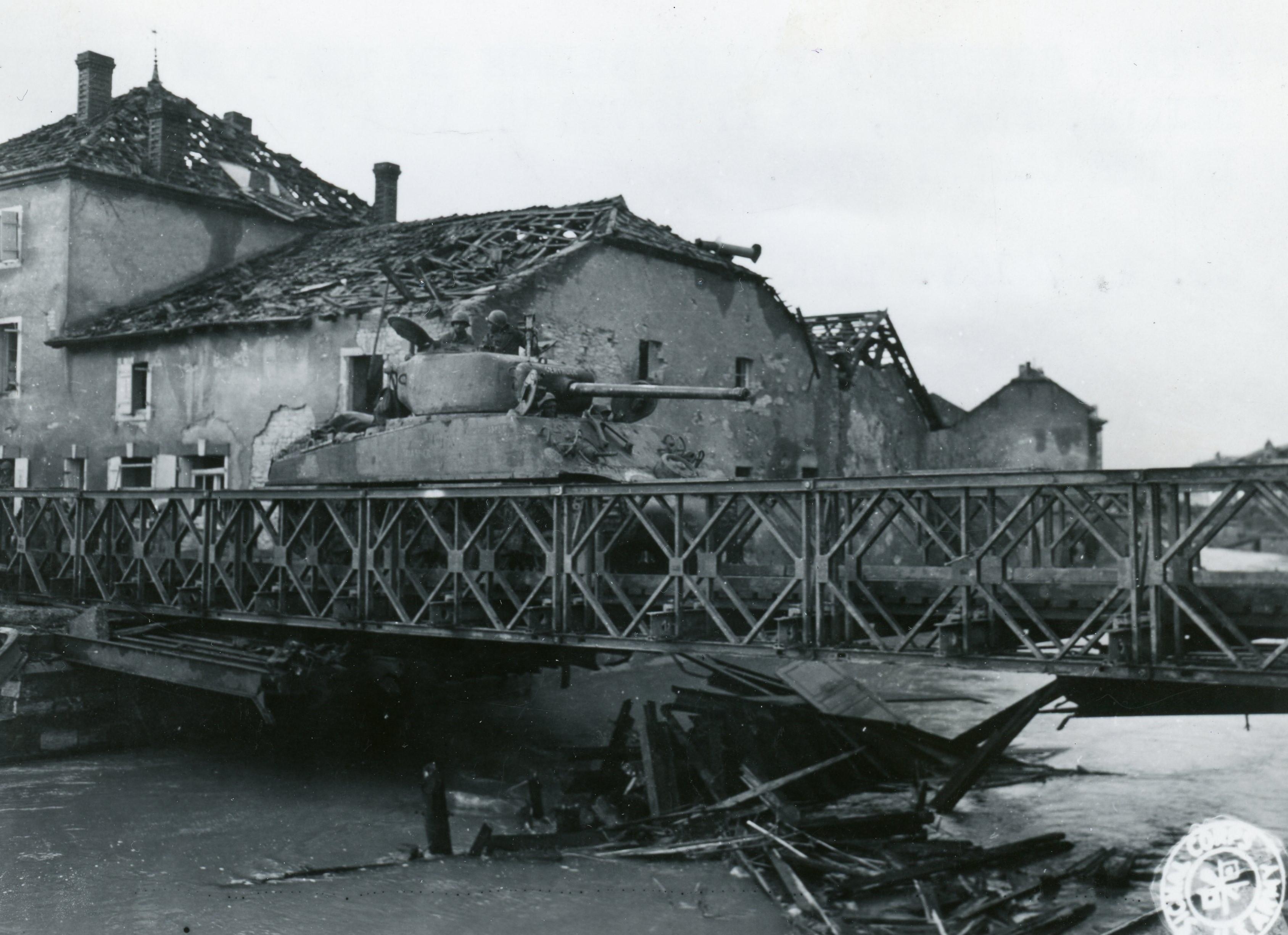 Historical image showing A M4 Sherman tank of the 761st Tank Battalion is crossing a Bailey Bridge in France of Black American soldiers during WWII