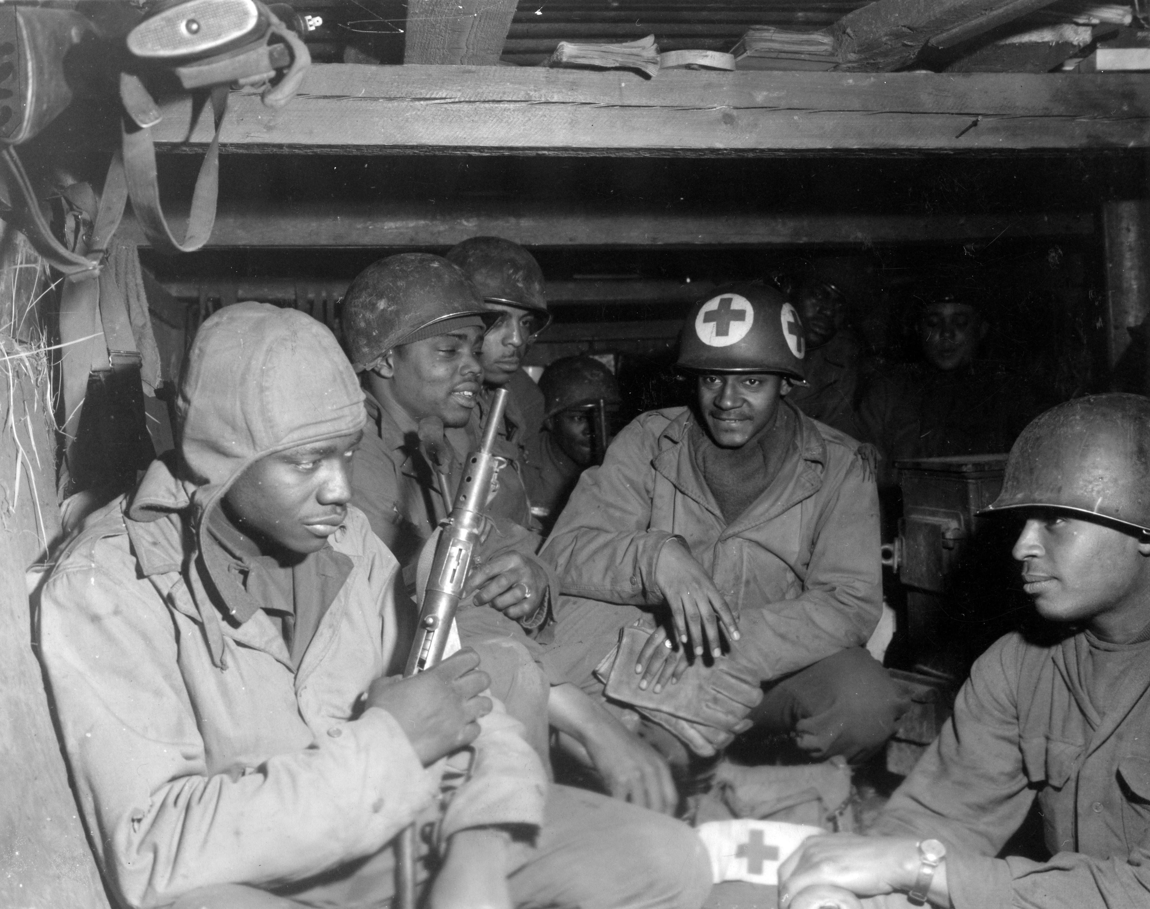 Historical image showing Several soldiers of the 777th Field Artillery Battalion in a dugout of Black American soldiers during WWII