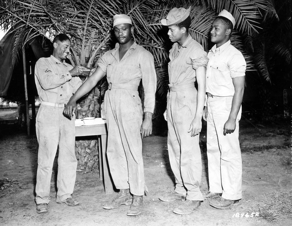 Historical image showing Private Glenn Moore, Warren, Ohio, is vaccinated by by T/5 Henry Edwards, member of a Medical Detachment. of Black American soldiers during WWII