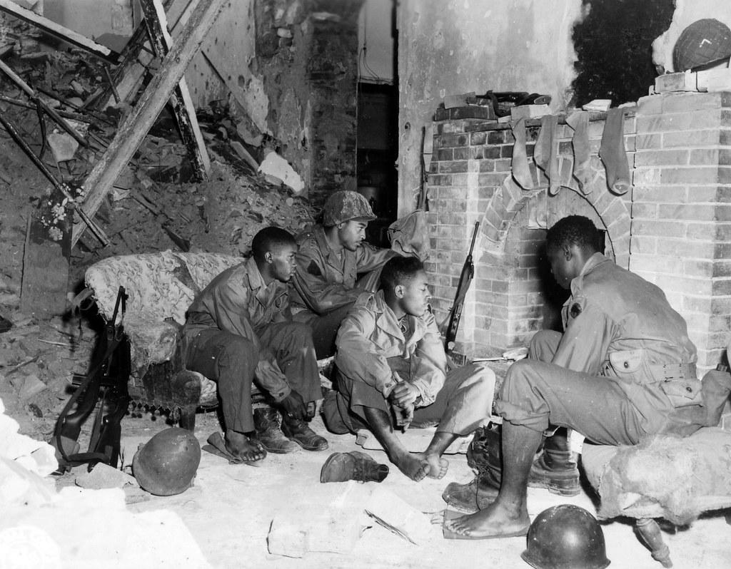 Historical image showing Soldiers of the 92nd Infantry Division are drying themselves in a ruined house. of Black American soldiers during WWII