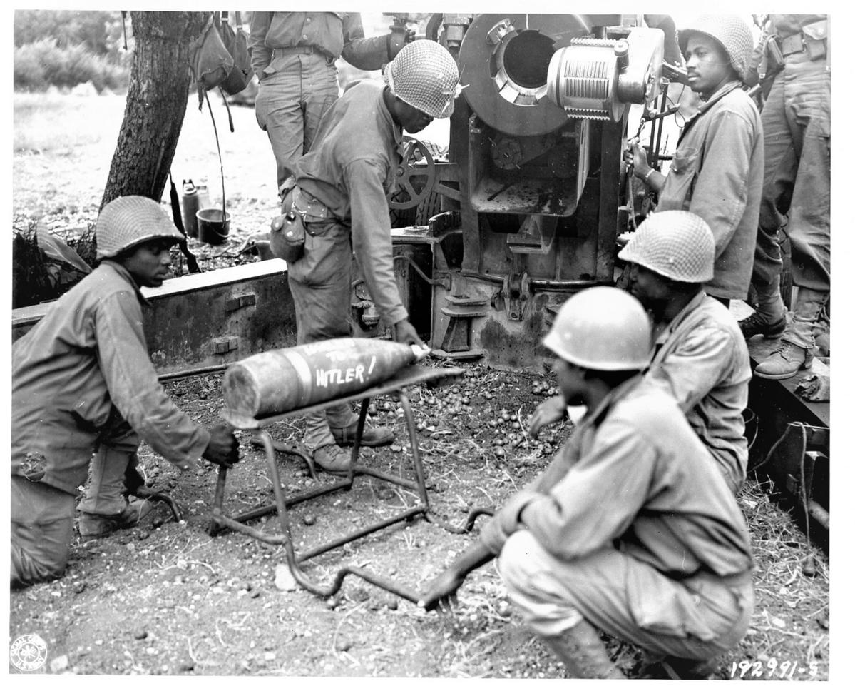 Historical image showing Soldiers of the 999th Field Artillery Battalion are about to fire another shell at a target. of Black American soldiers during WWII