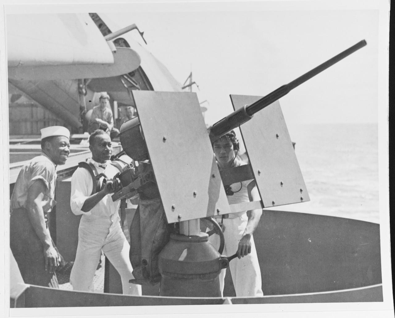 Historical image showing Mess attendants of the USS Copahee (ACV-12) man a 20mm machine gun of Black American soldiers during WWII