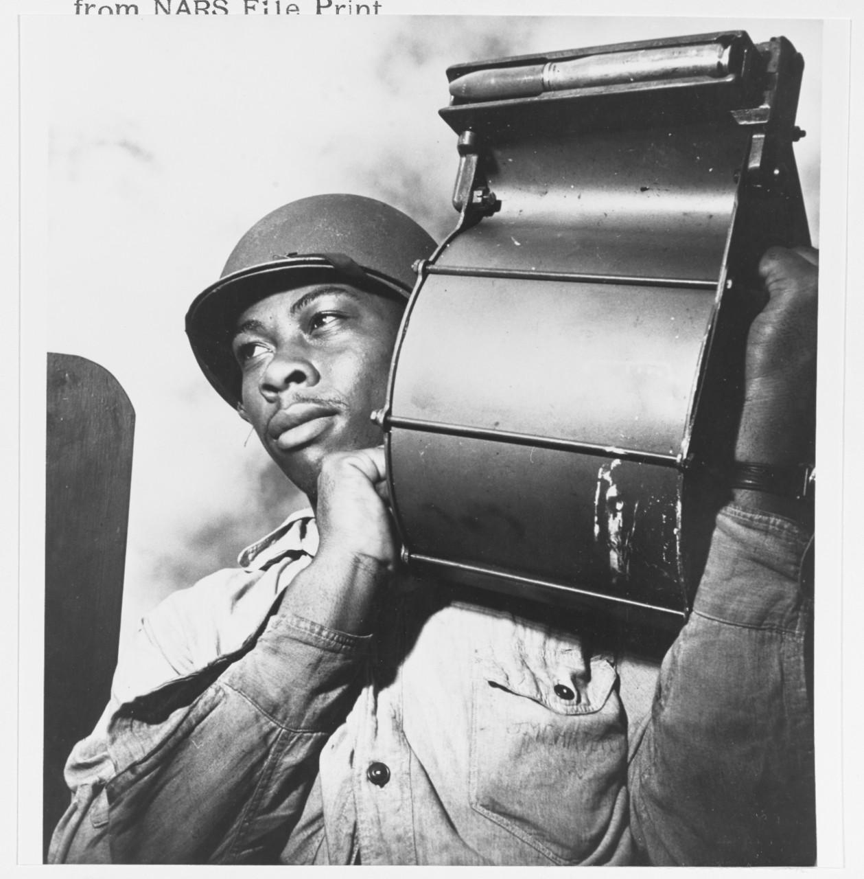 Historical image showing Miles King carries a loaded 20mm machine gun magazine of Black American soldiers during WWII