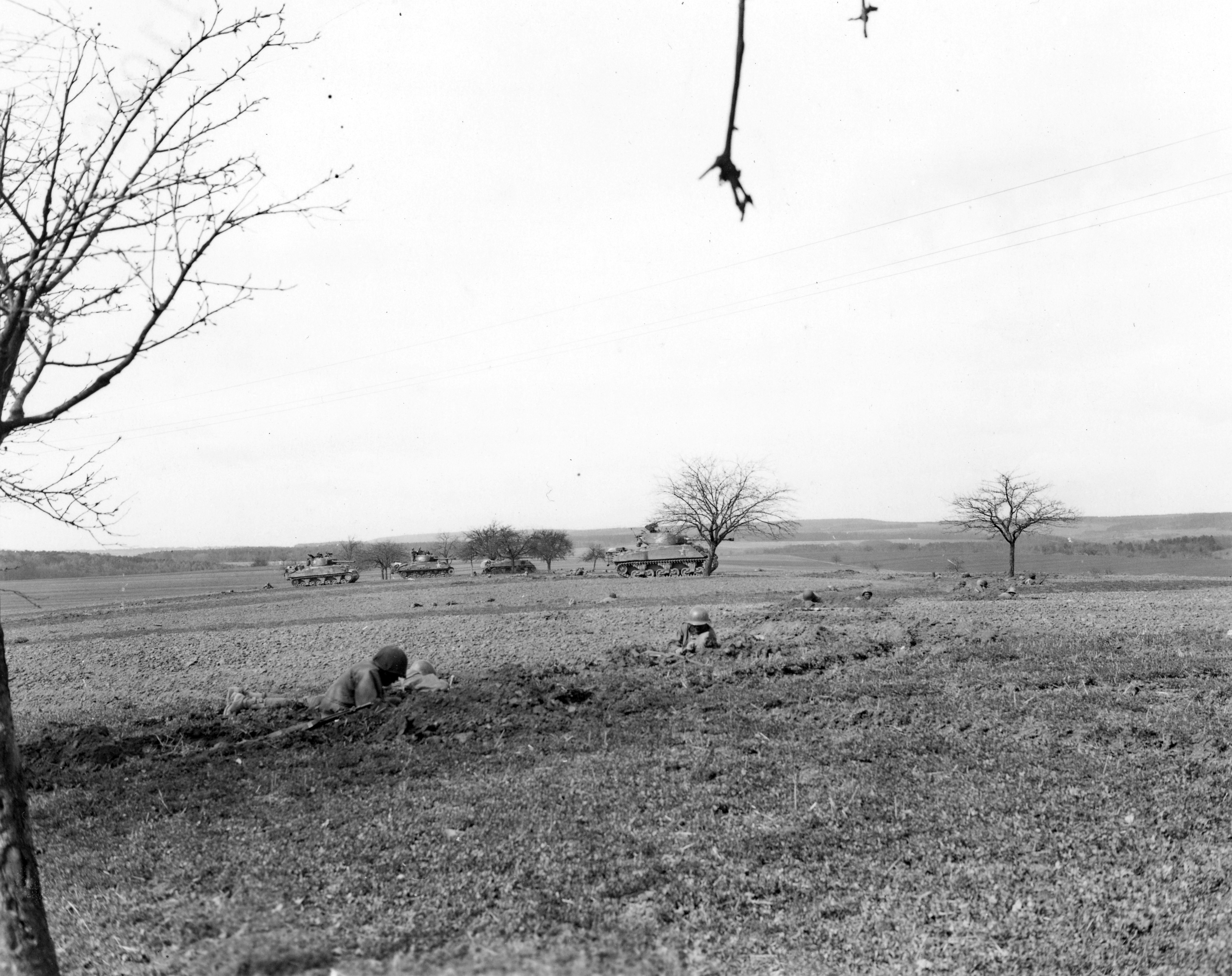 Historical image showing Before attack: armored infantry dug-in in a field prior to attacking Nassig, Germany. of Black American soldiers during WWII