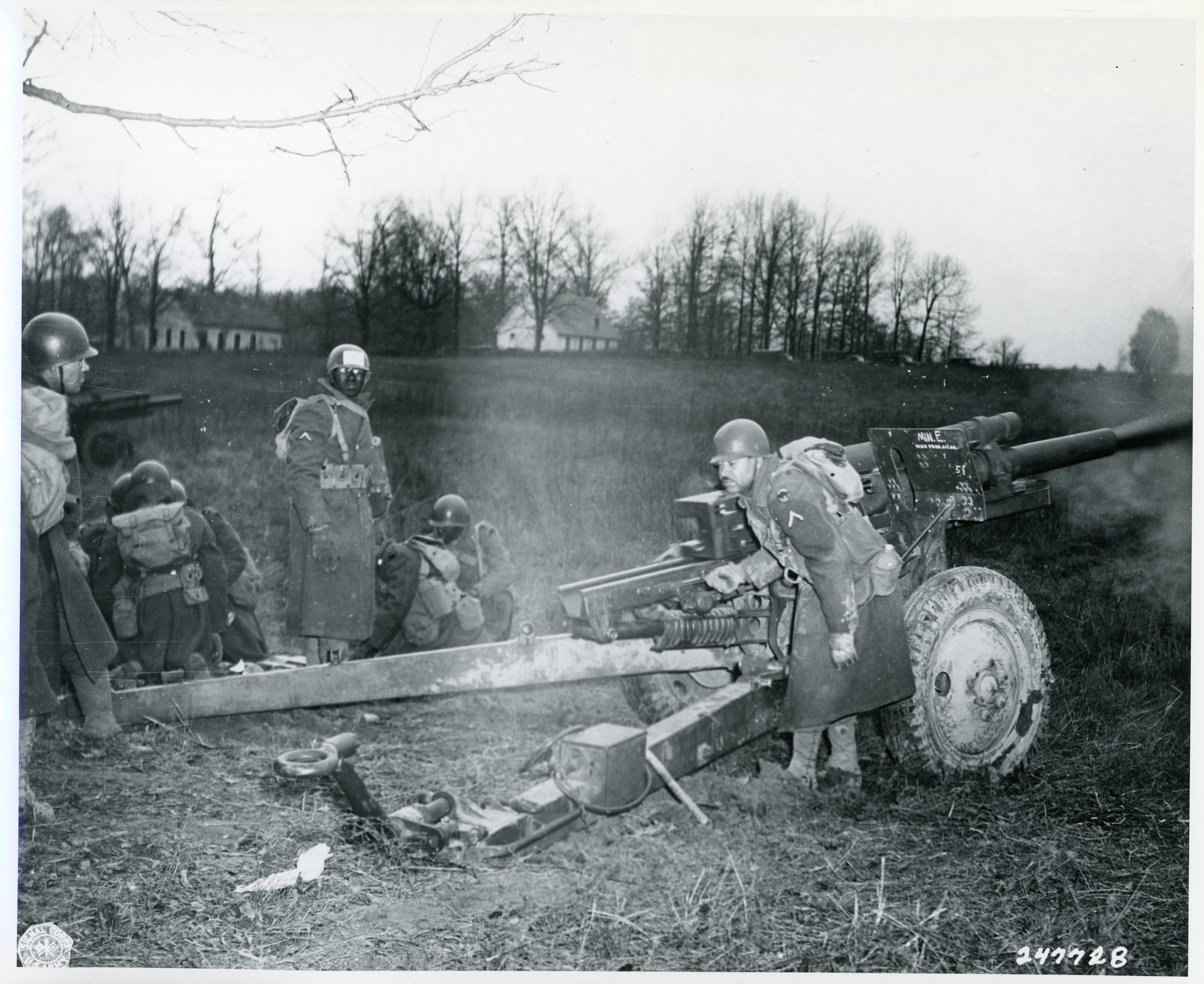 Historical image showing A Black American soldier fires a 105mm howitzer. of Black American soldiers during WWII